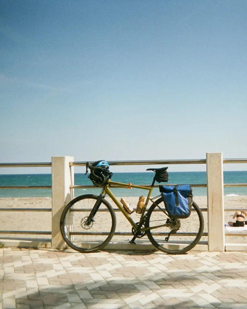 Un vélo appuyé à la rambarde d’une promenade face à la plage