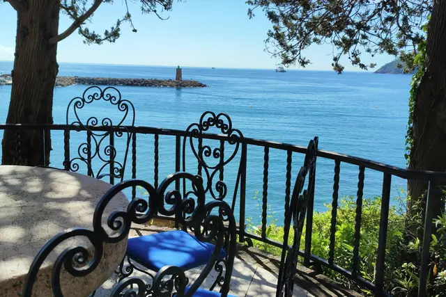 Table et chaises en fer forgé sur une terrasse au-dessus de la mer
